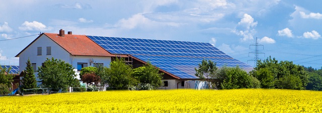 Bauernhof mit Solarzellen im Rapsfeld